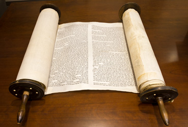 A Torah scroll partially open on a table.